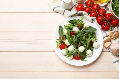 Photo of Tasty salad with arugula, spinach, mozzarella cheese and tomatoes on wooden table, flat lay. Space for text