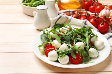 Photo of Tasty salad with arugula, spinach, mozzarella cheese and tomatoes on wooden table, closeup