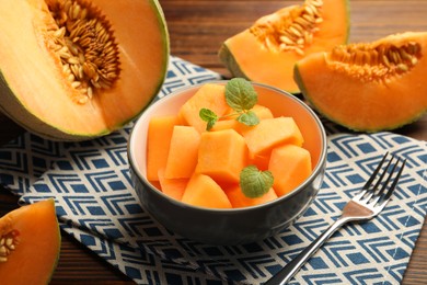 Photo of Pieces of ripe Cantaloupe melon in bowl and fork on table, closeup