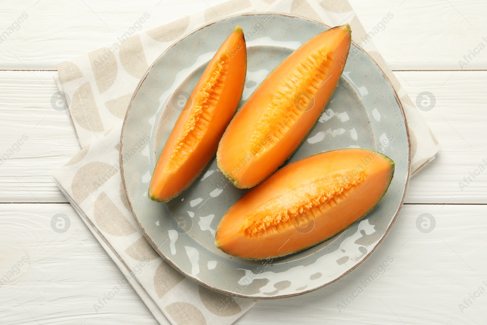 Photo of Pieces of fresh Cantaloupe melon on white wooden table, top view