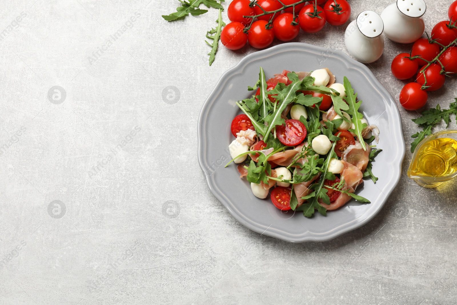 Photo of Tasty salad with arugula on grey textured table, flat lay. Space for text