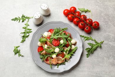 Photo of Tasty salad with arugula on grey textured table, flat lay