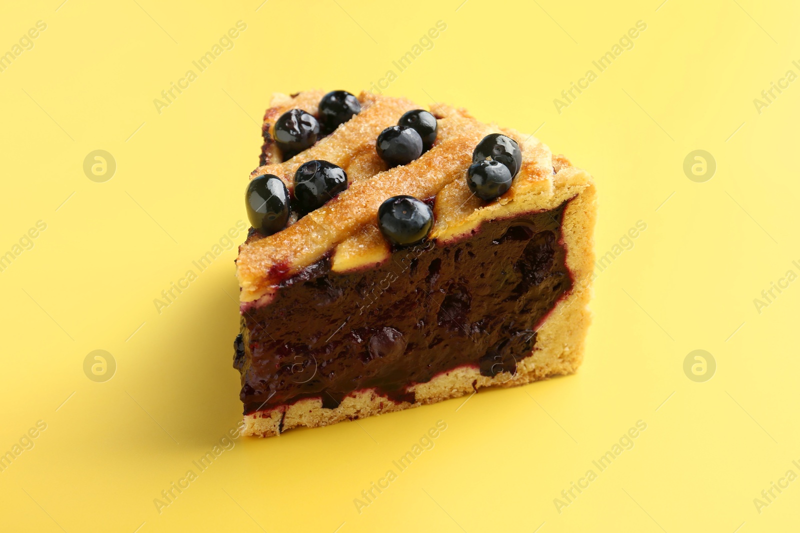 Photo of Slice of homemade blueberry pie on yellow background