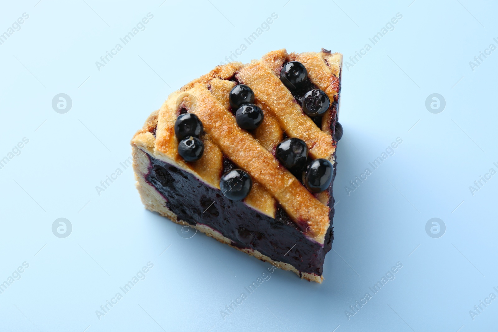 Photo of Slice of homemade blueberry pie on light blue background