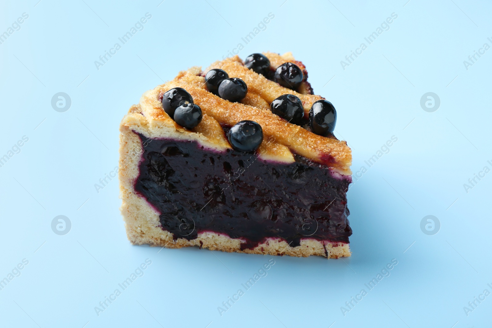 Photo of Slice of homemade blueberry pie on light blue background