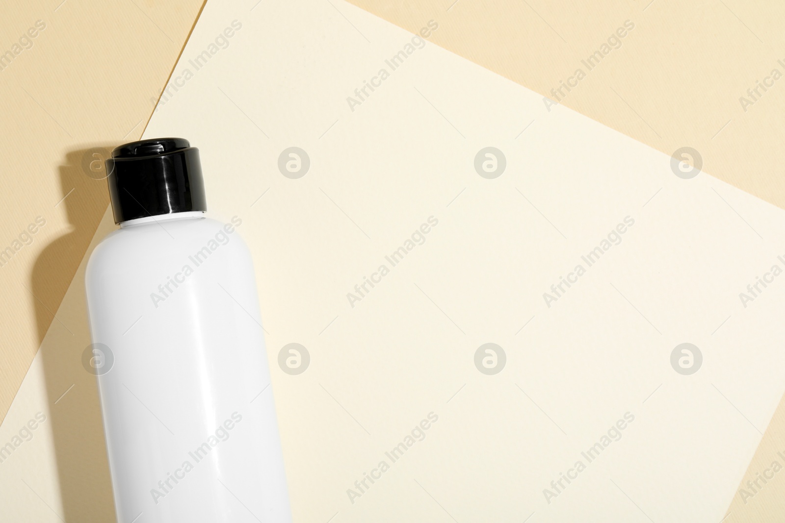 Photo of Shampoo in bottle on beige background, top view. Space for text