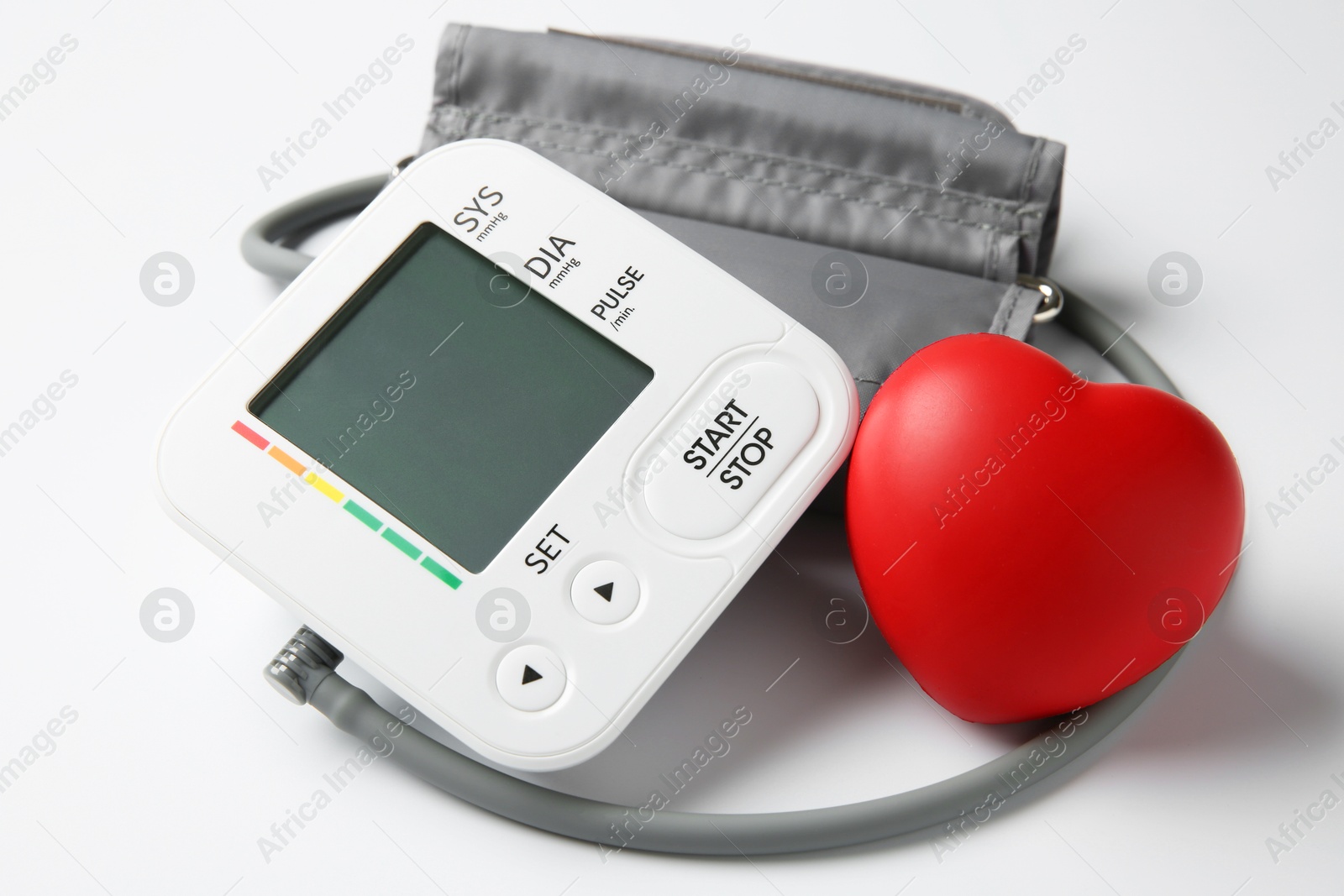 Photo of Blood pressure measuring device and squeeze heart on white background, closeup