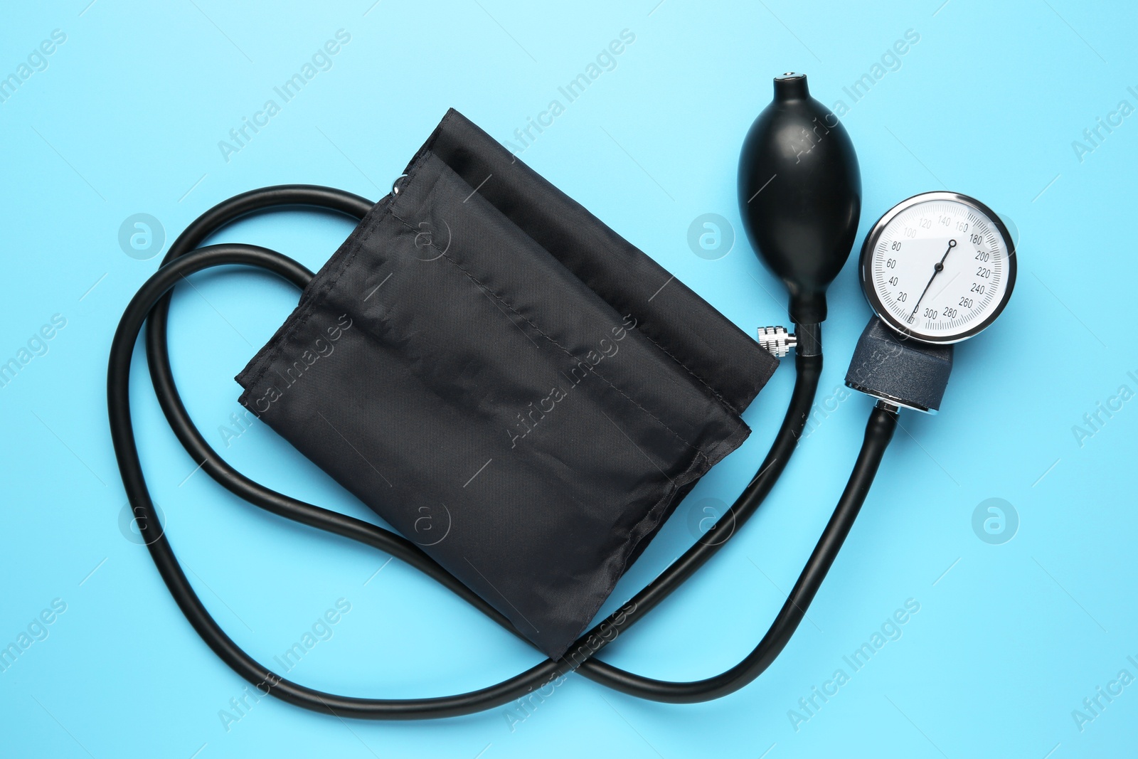 Photo of Blood pressure measuring device on light blue background, top view