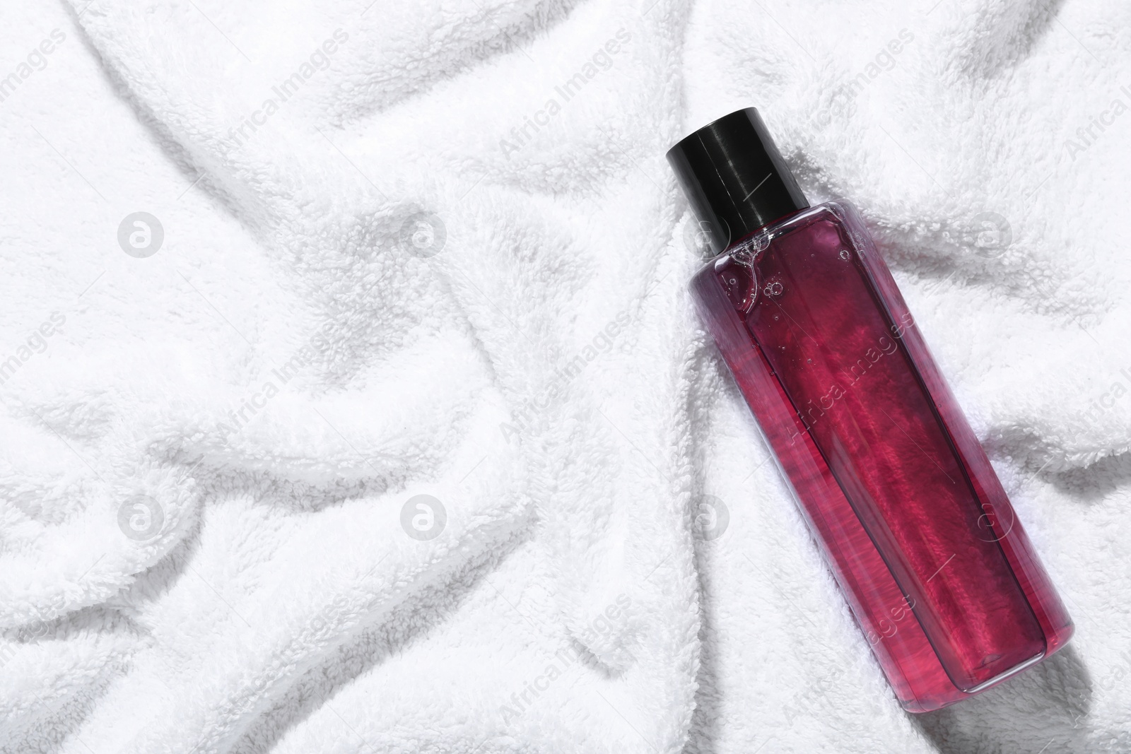 Photo of Shampoo in bottle on soft towel, top view. Space for text