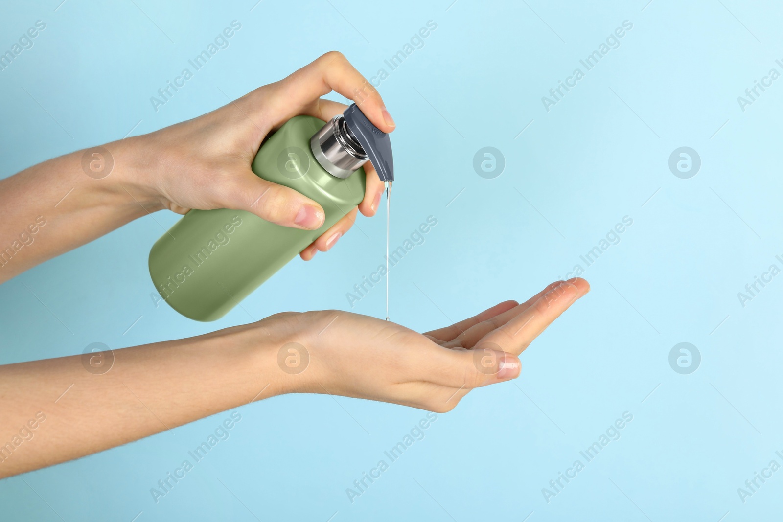 Photo of Woman pouring shampoo onto hand on light blue background, closeup