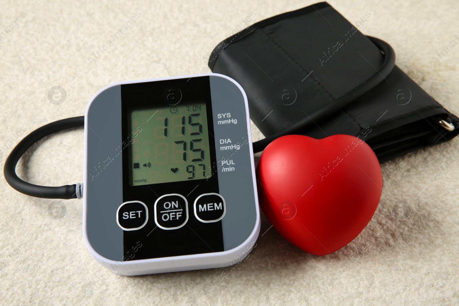 Photo of Blood pressure measuring device and squeeze heart on light textured background, closeup