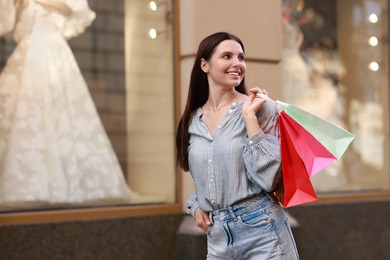 Happy woman with colorful shopping bags outdoors, space for text