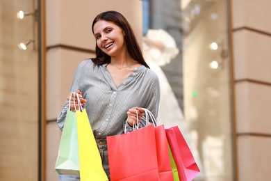 Happy woman with colorful shopping bags outdoors