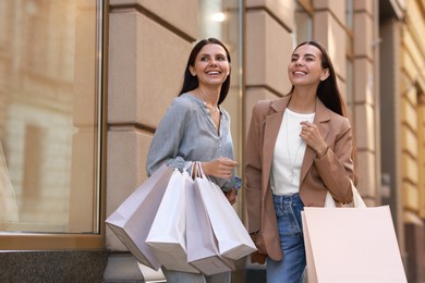 Photo of Happy women with colorful shopping bags outdoors