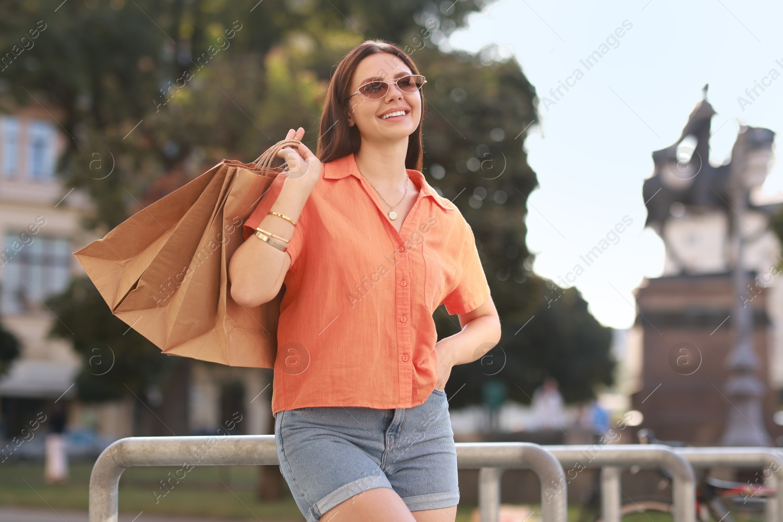 Photo of Happy woman with many shopping bags outdoors