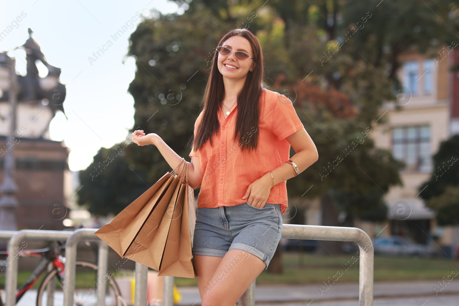 Photo of Happy woman with many shopping bags outdoors