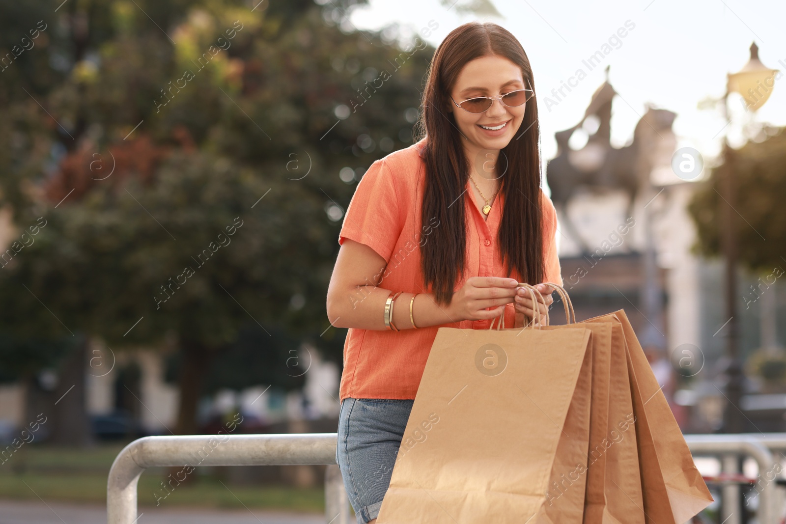 Photo of Happy woman with many shopping bags outdoors, space for text