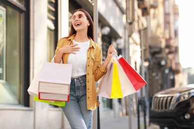 Photo of Happy woman with colorful shopping bags outdoors