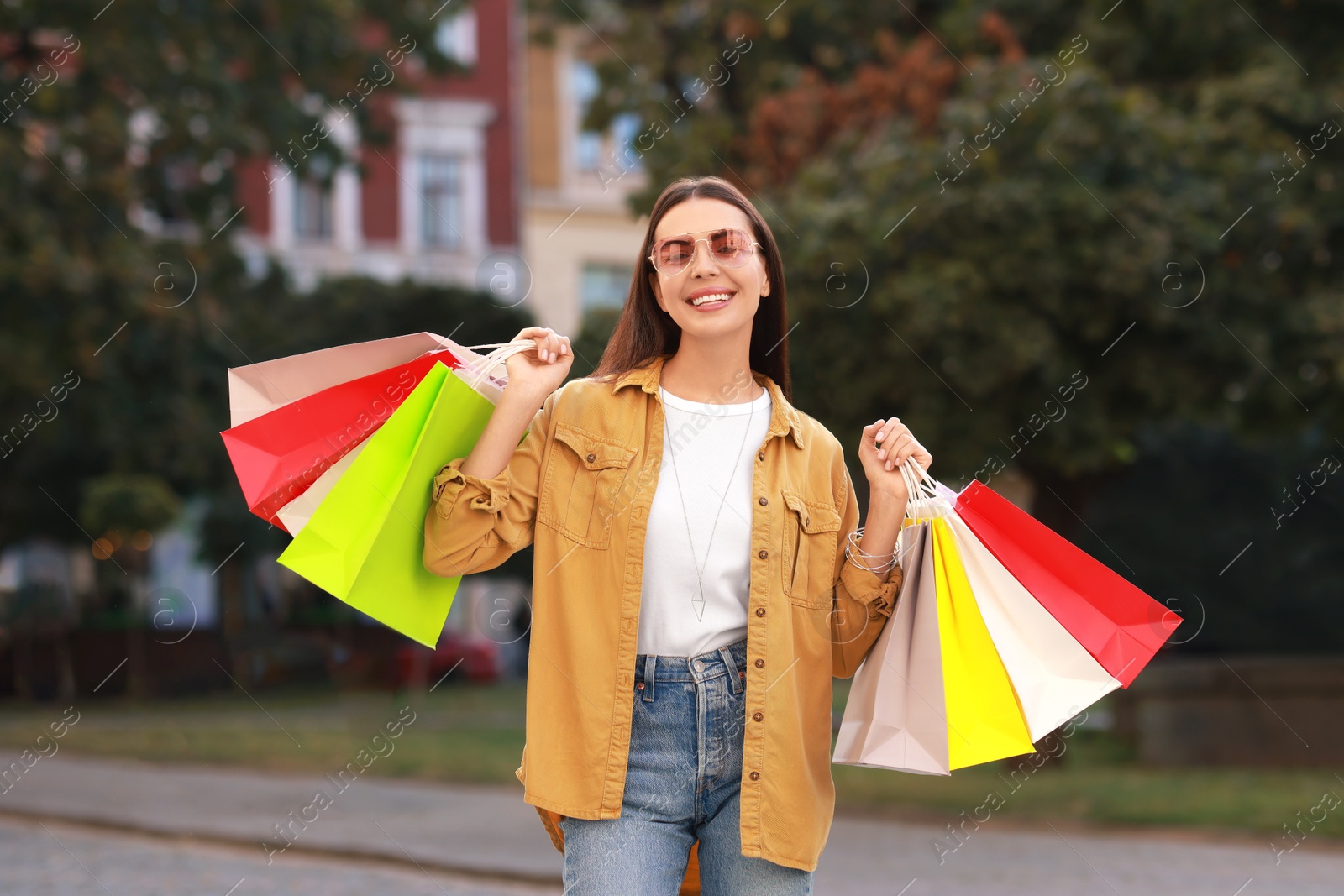 Photo of Happy woman with colorful shopping bags outdoors