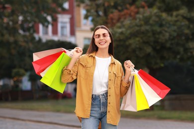 Happy woman with colorful shopping bags outdoors