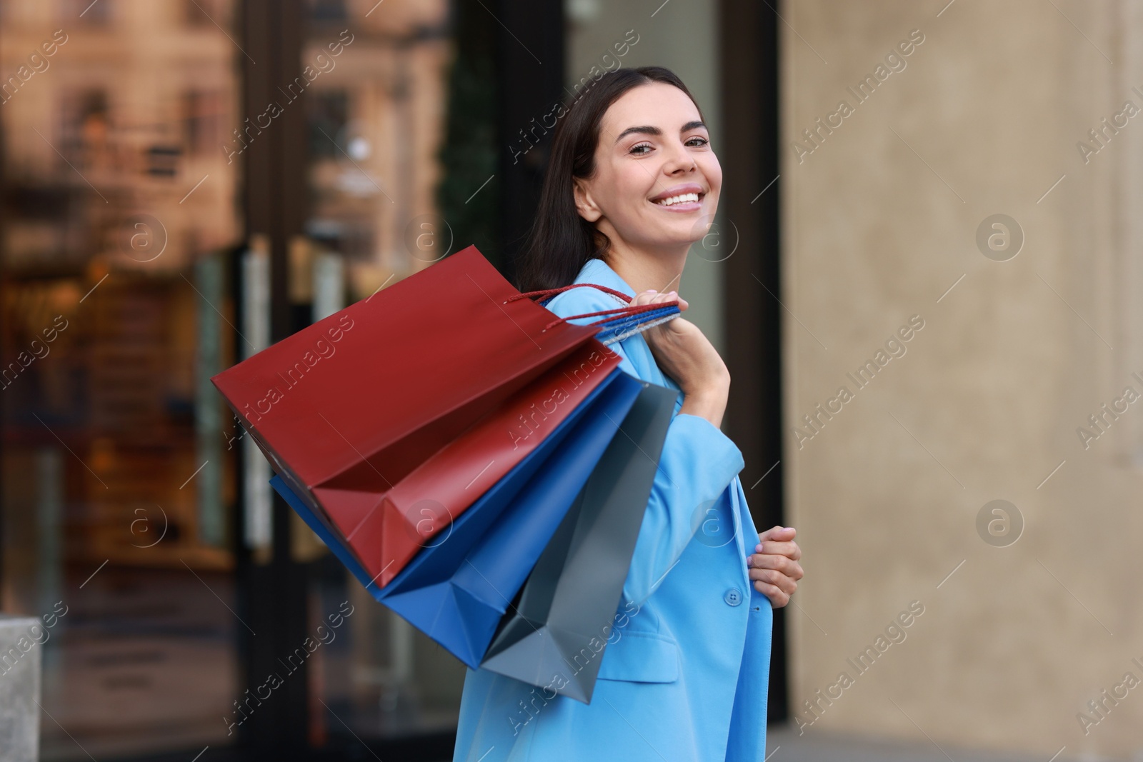 Photo of Happy woman with colorful shopping bags outdoors