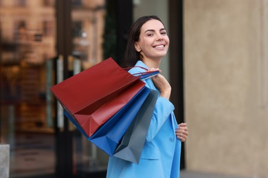 Happy woman with colorful shopping bags outdoors