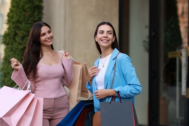 Happy women with colorful shopping bags outdoors