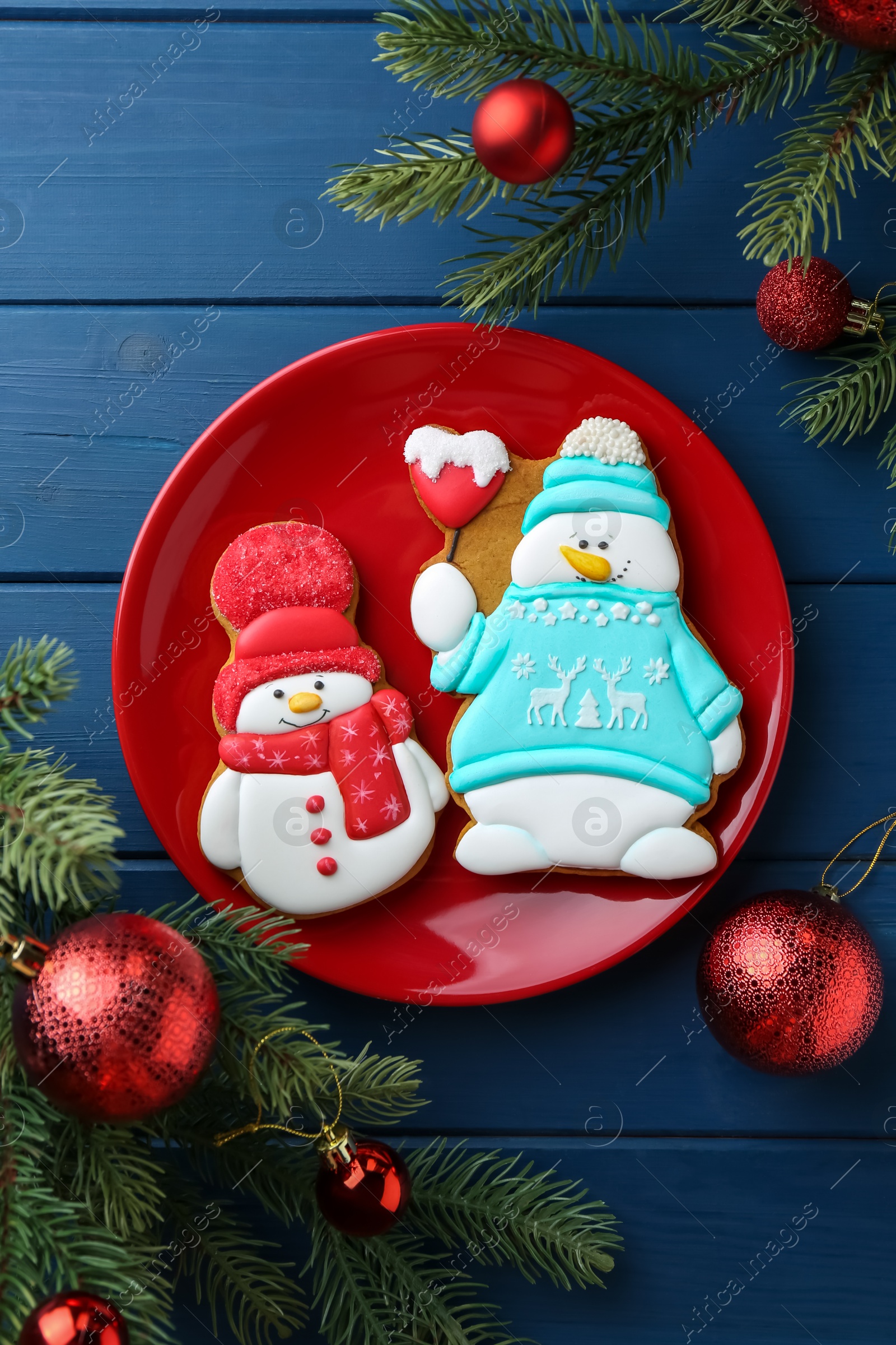 Photo of Delicious cookies in shape of snowmen and Christmas decor on blue wooden table, flat lay