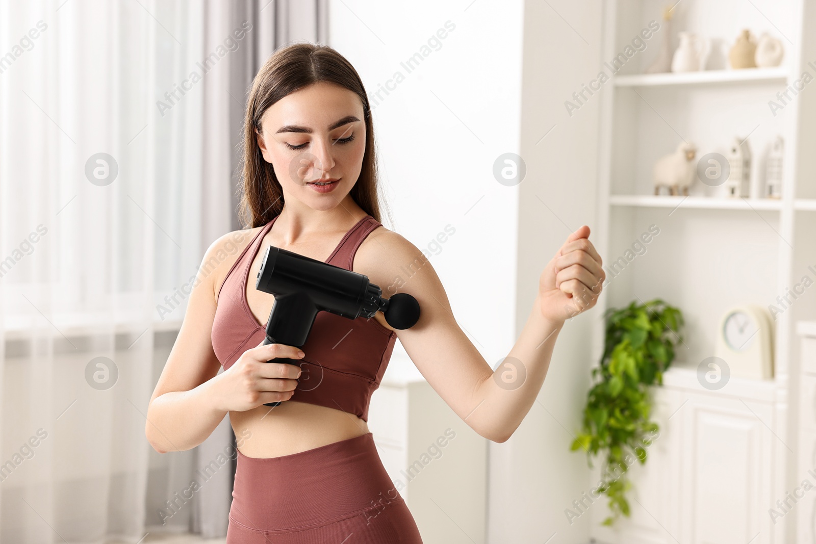 Photo of Woman using percussive massager to relieve bicep at home