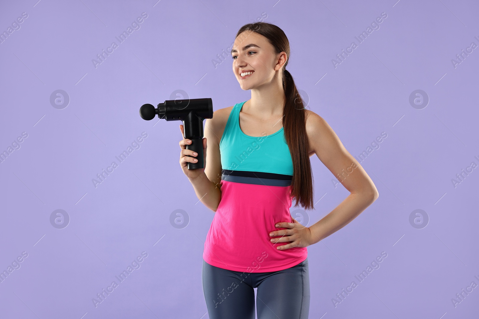 Photo of Young woman with percussive massager on light purple background