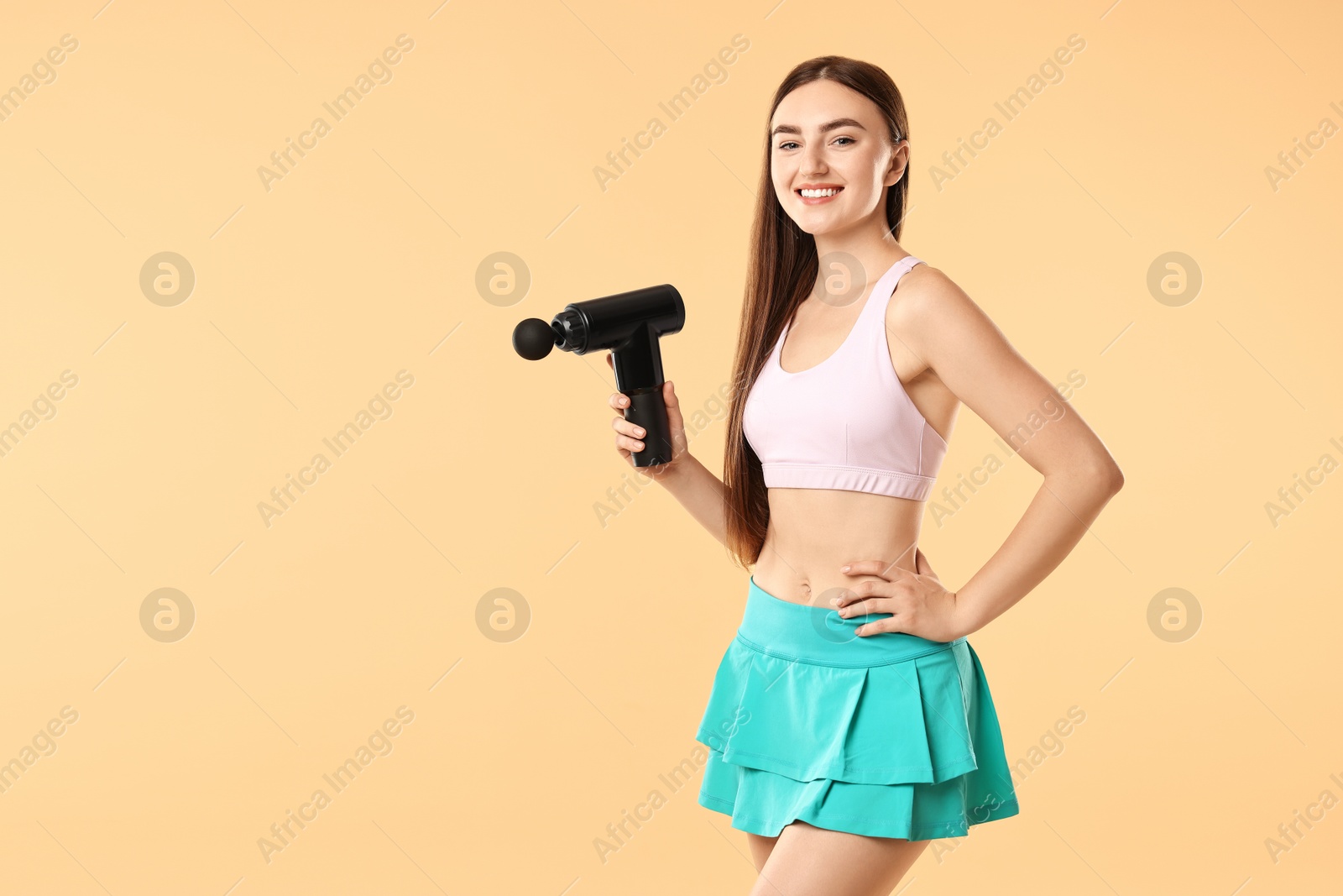 Photo of Young woman with percussive massager on beige background. Space for text