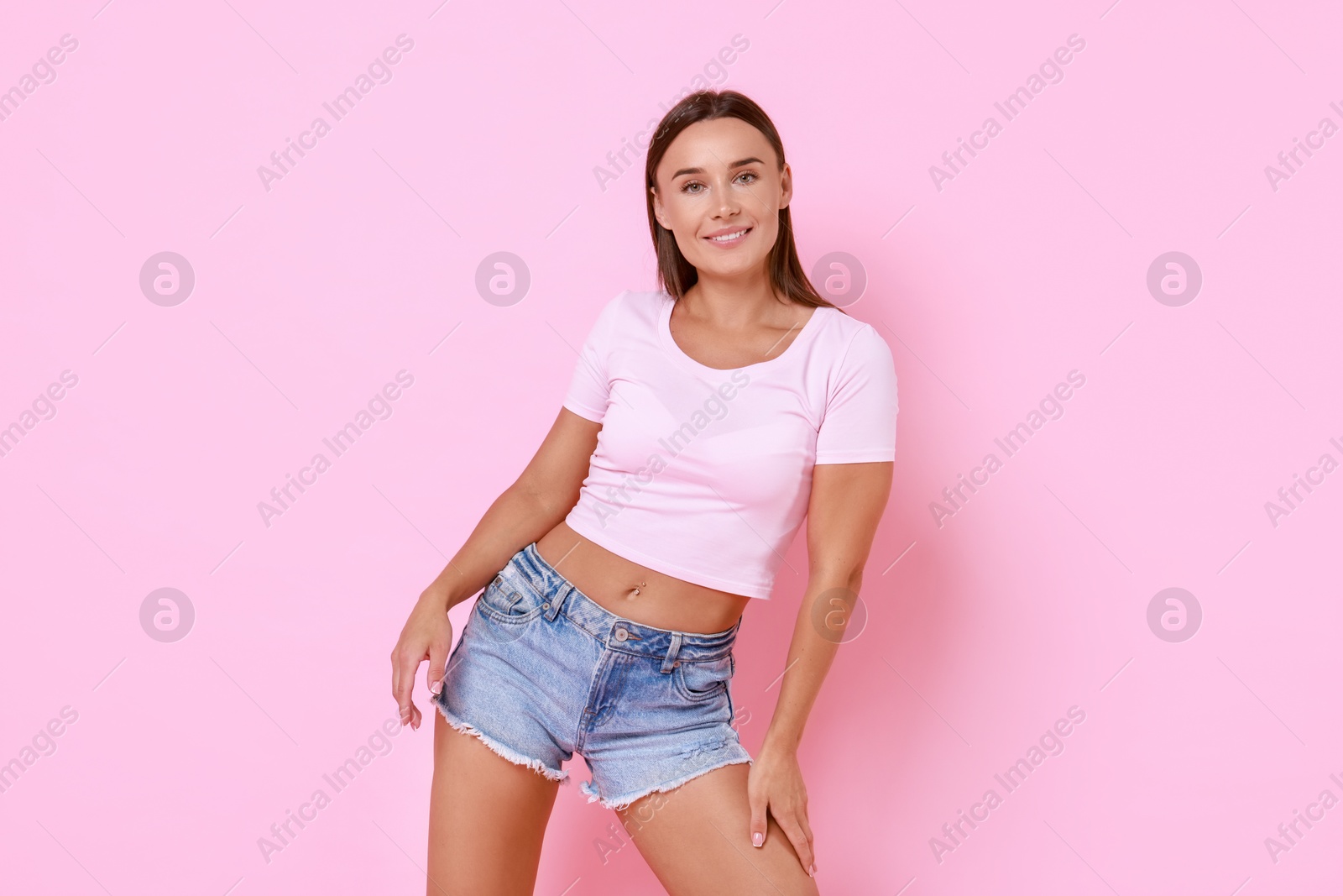 Photo of Beautiful woman wearing stylish denim shorts on pink background