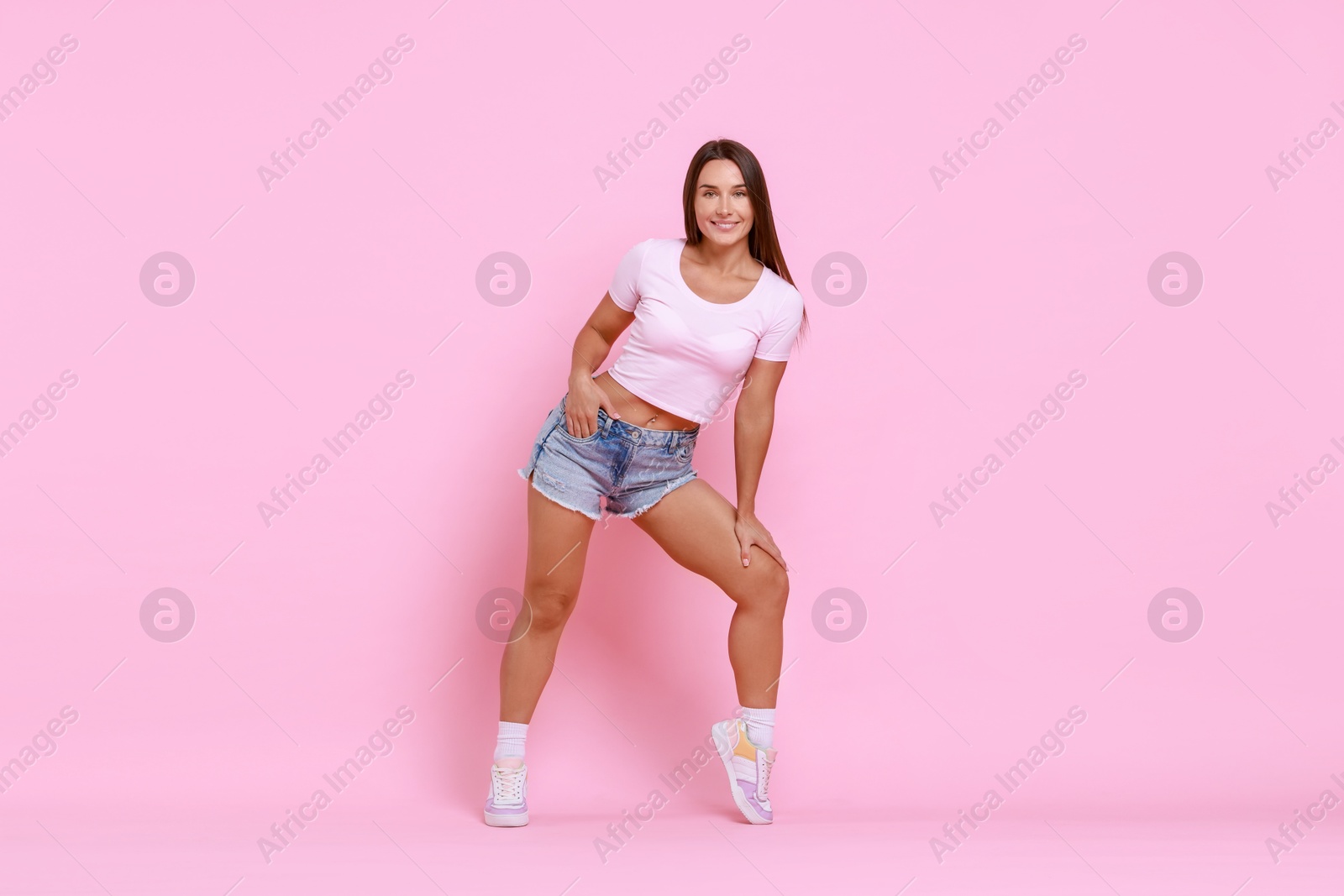 Photo of Beautiful woman wearing stylish denim shorts on pink background