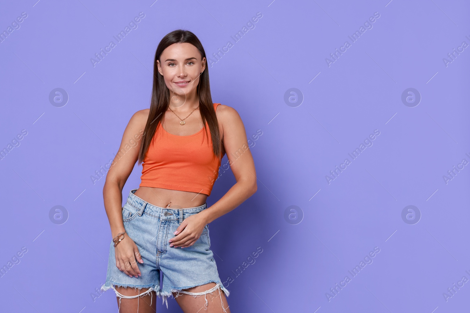 Photo of Beautiful woman wearing stylish denim shorts on violet background, space for text