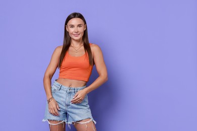 Photo of Beautiful woman wearing stylish denim shorts on violet background, space for text