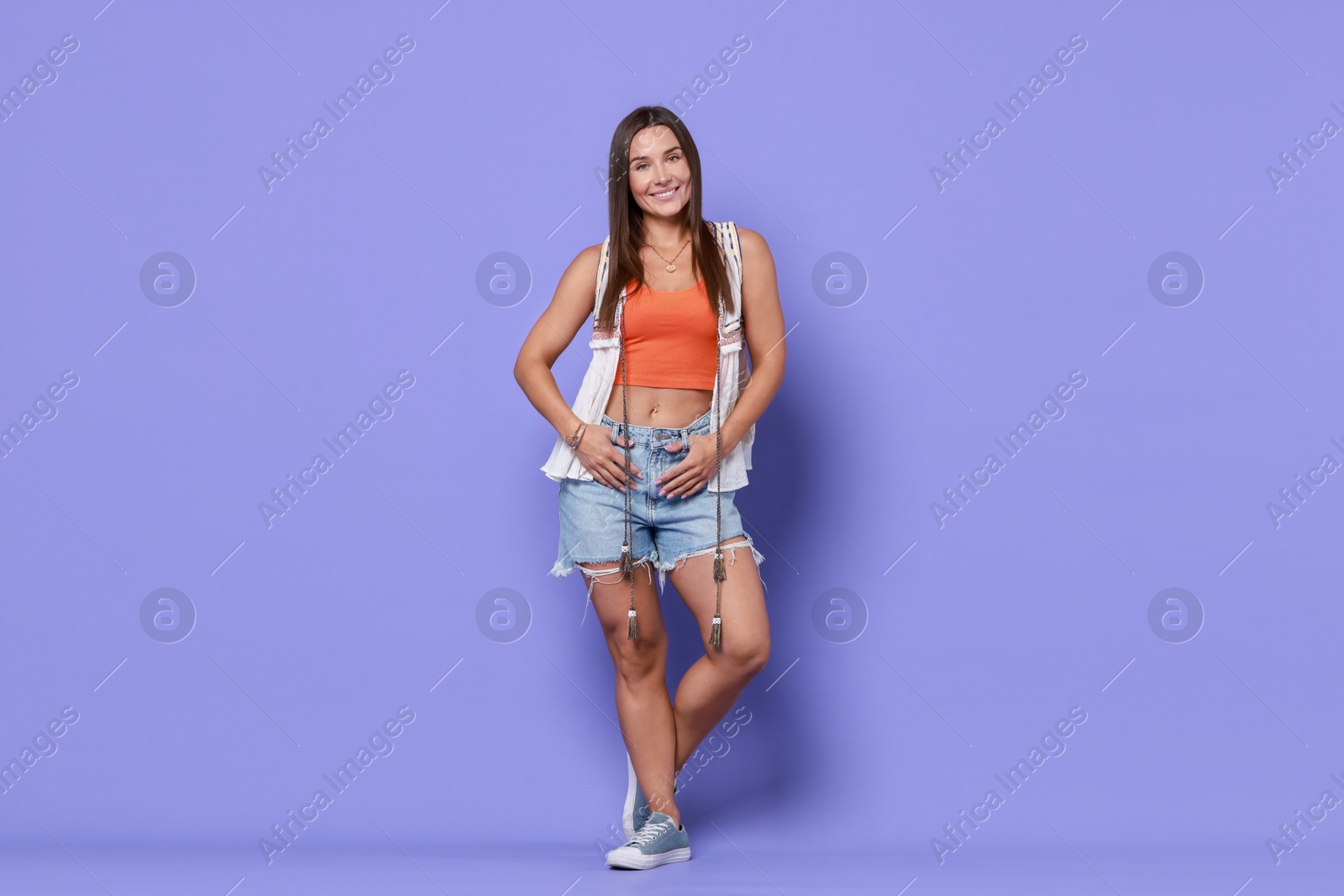 Photo of Beautiful woman wearing stylish denim shorts on violet background