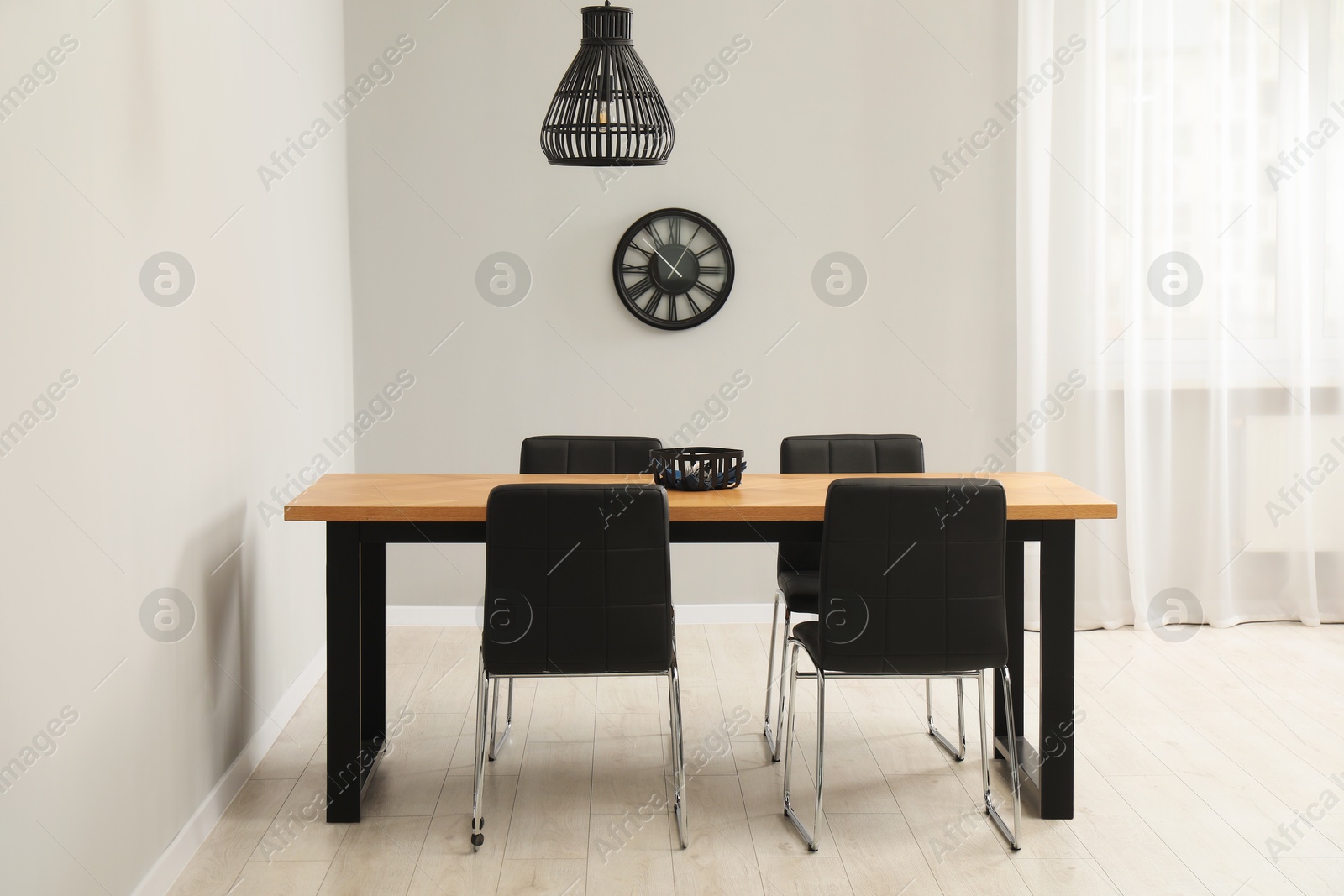 Photo of Wooden table with black chairs in stylish dining room