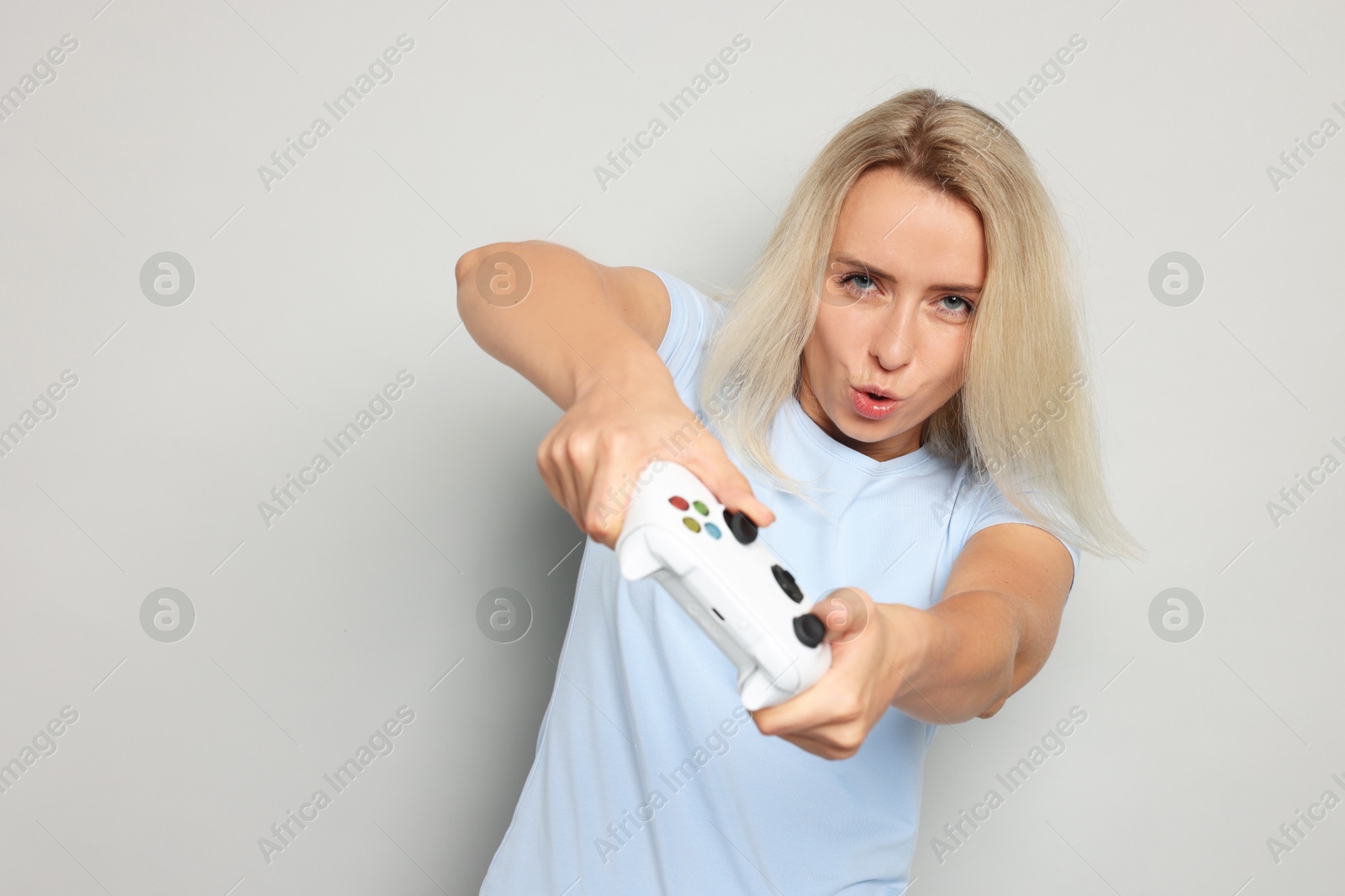 Photo of Woman playing video games with controller on gray background, space for text