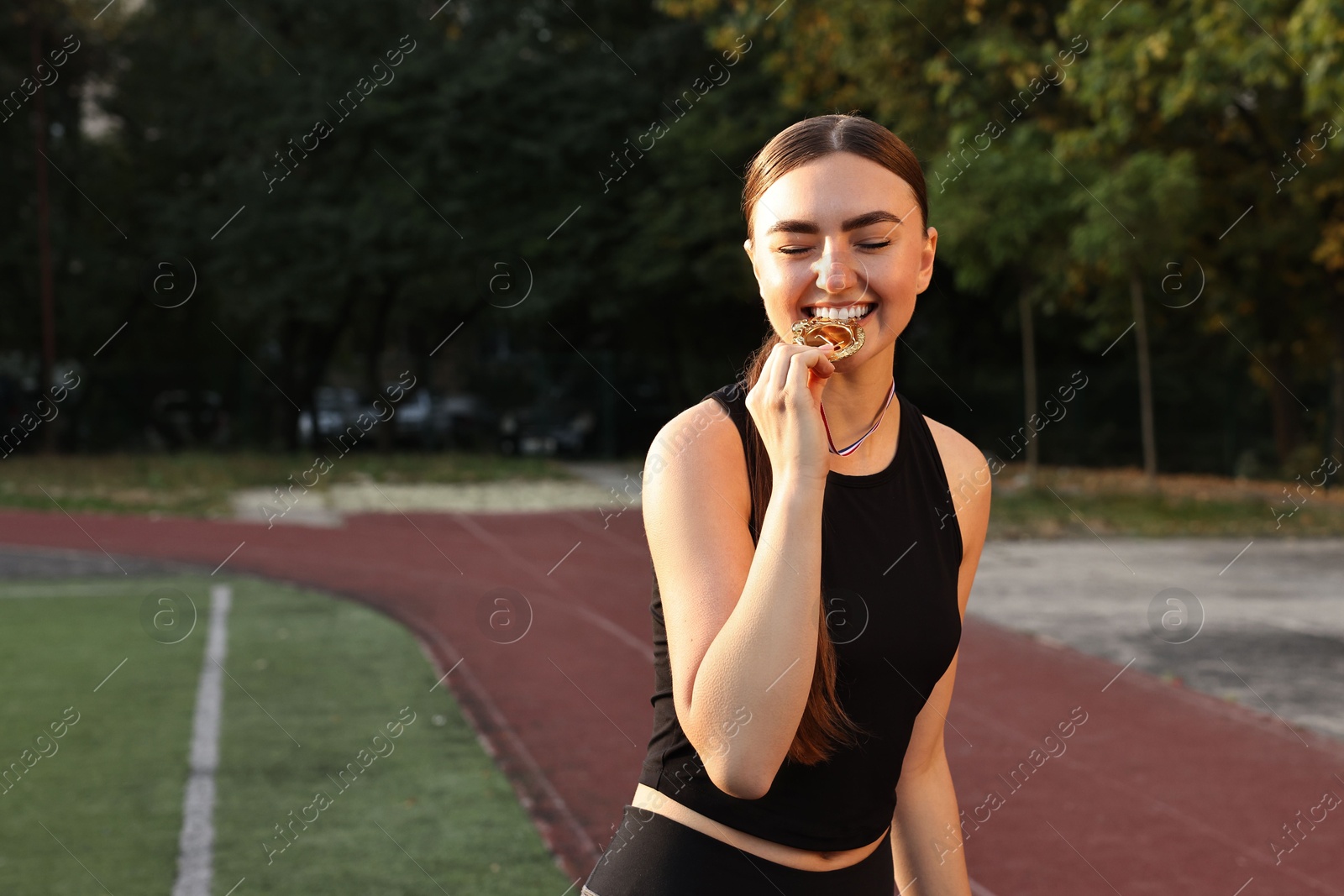 Photo of Happy winner with golden medal at stadium. Space for text