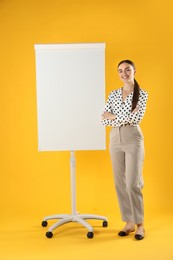 Happy woman near flip chart on orange background. Mockup for design