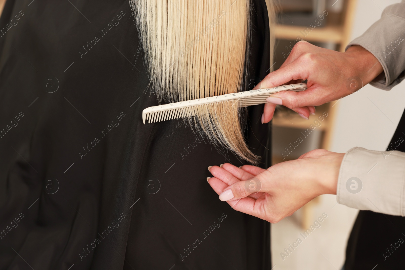 Photo of Hairdresser combing woman's hair in salon, closeup