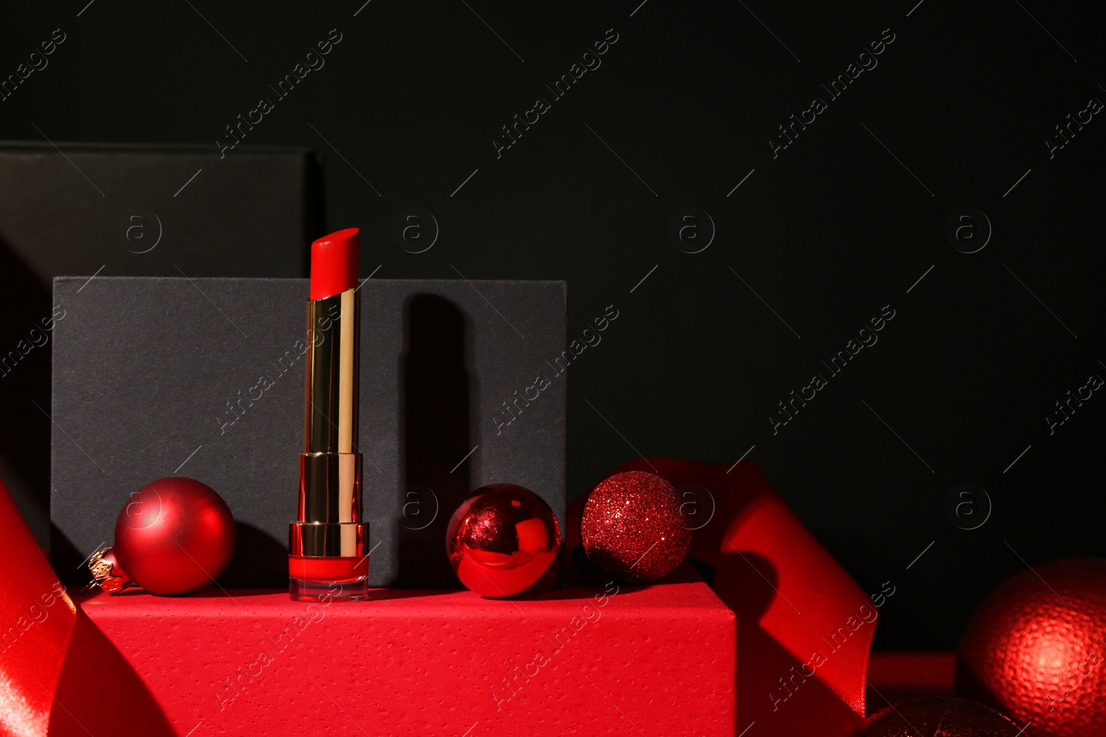 Photo of Christmas present. Red lipstick, boxes and festive decor against black background. Space for text