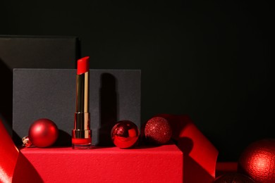 Photo of Christmas present. Red lipstick, boxes and festive decor against black background. Space for text