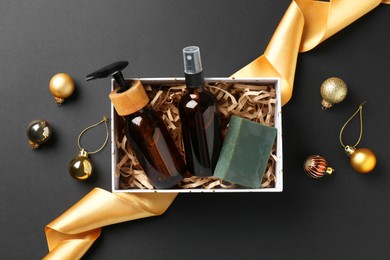 Cosmetic products in box as Christmas gift and festive decor on black background, flat lay