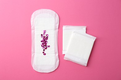 Photo of Menstrual pads and sequins on pink background, top view