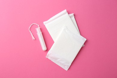 Photo of Menstrual pads and tampon on pink background, top view