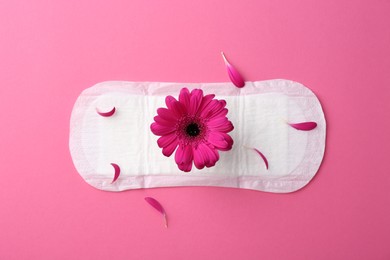 Photo of Menstrual pad with flower on pink background, top view