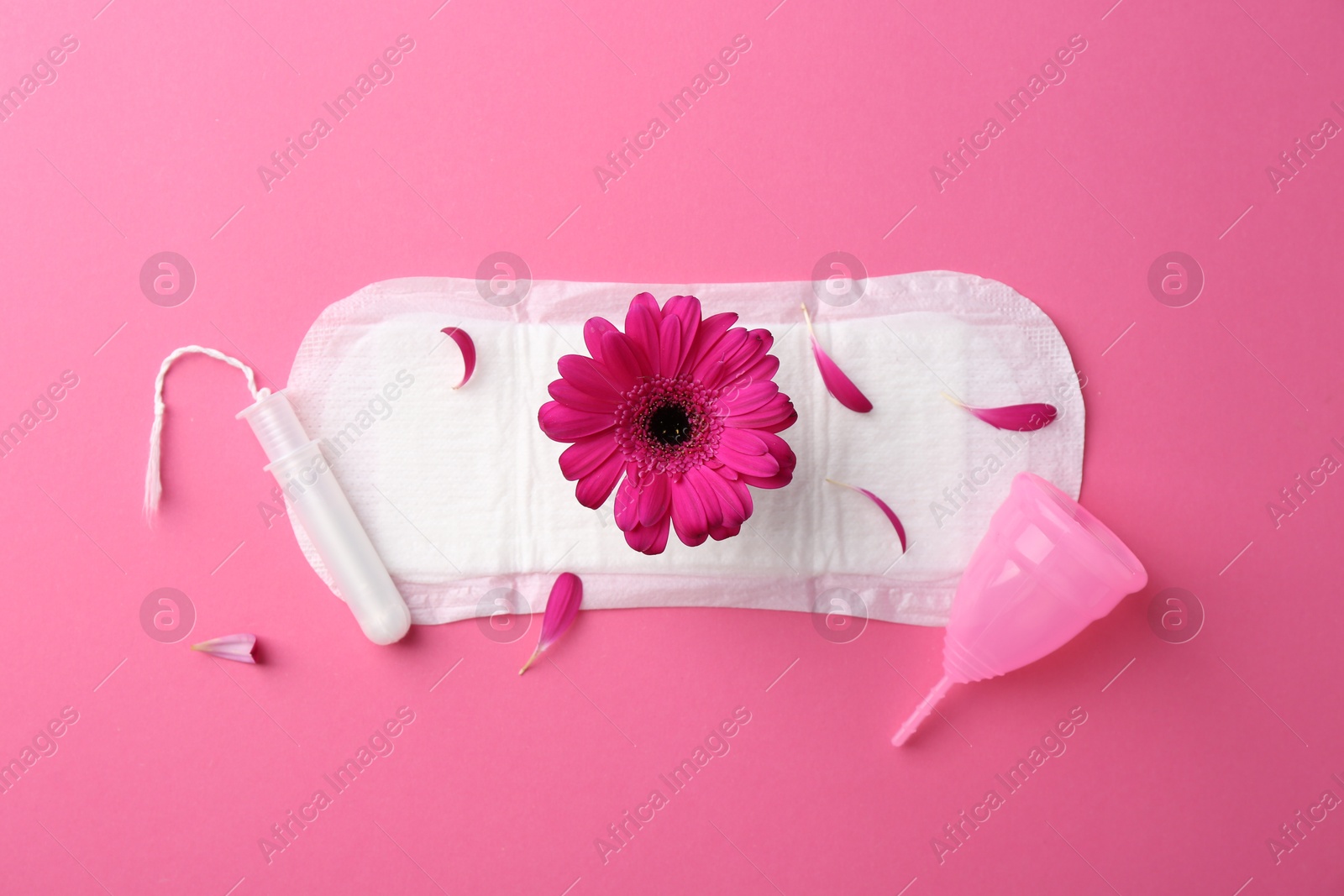 Photo of Pad with flower, tampon and menstrual cup on pink background, top view