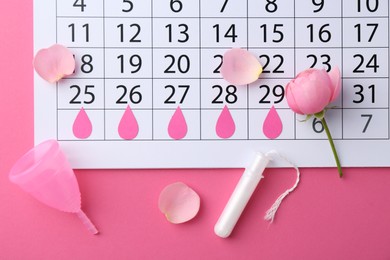 Photo of Flat lay composition with calendar and menstrual products on pink background