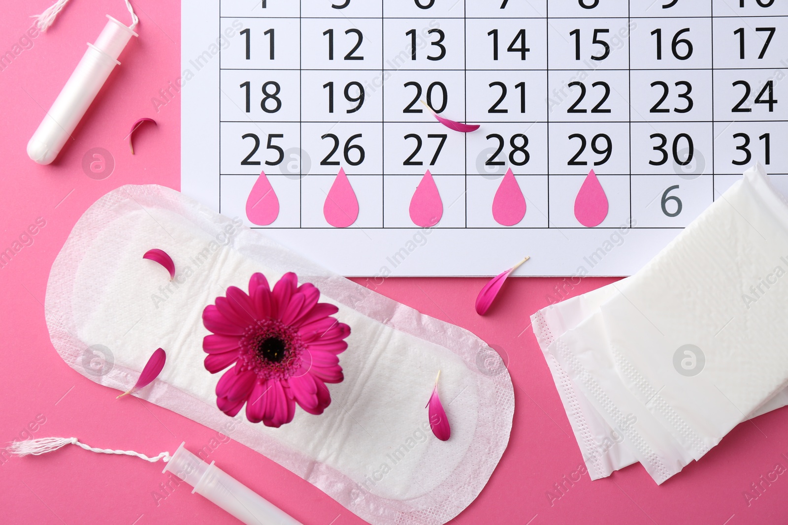 Photo of Flat lay composition with calendar and menstrual products on pink background